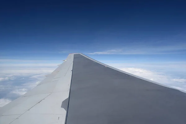 View from the porthole of an airplane flying above the clouds. Aircraft wing.