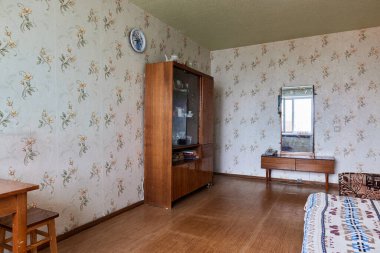 Leningrad Projesi 'ndeki Eski Sovyet fakir iç mimarisi örneği House. Eski büfe, masa, sandalyeler, yatak. Döşeme berbat. Duvardaki yırtık duvar kağıdı. Emeklilerin dairesi. Seçici odak.