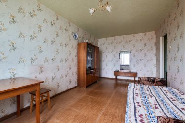 Leningrad Projesi 'ndeki Eski Sovyet fakir iç mimarisi örneği House. Eski büfe, masa, sandalyeler, yatak. Döşeme berbat. Duvardaki yırtık duvar kağıdı. Emeklilerin dairesi. Seçici odak.