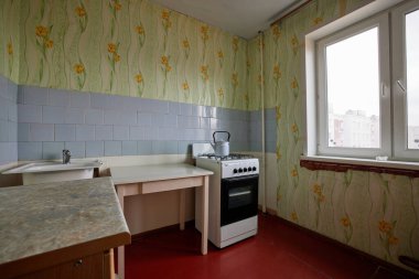 Kazan, Tataristan, Rusya - Ekim 2021: Khruschev Evi 'ndeki eski Sovyet fakir mutfak örneği. Yıllanmış soba, masa. Döşeme berbat. Duvardaki parçalanmış fayanslar. Emeklilerin dairesi.