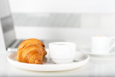 Kahve, kruvasan ve dizüstü bilgisayar masada. Kahvaltı..