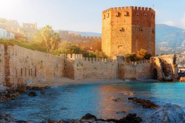 Türkiye 'nin Antalya bölgesindeki Alanya yarımadasındaki Kyzyl Kule kulesi yakınlarındaki antik bir tersanenin manzarası gün batımında.