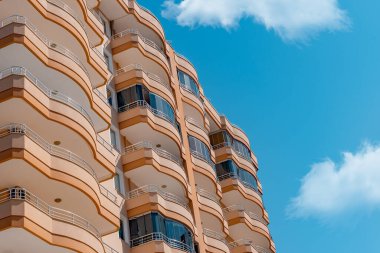 Fragment of a modern residential exterior of an apartment building. View of urban real estate and condo architecture. Blue sky