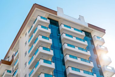 Mavi gökyüzüne karşı balkonları olan bir apartmanın köşesinde..