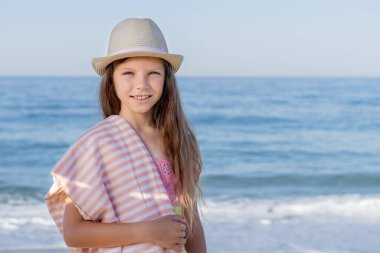 Akdeniz 'in arka planında havlusu olan şapkalı genç kız..