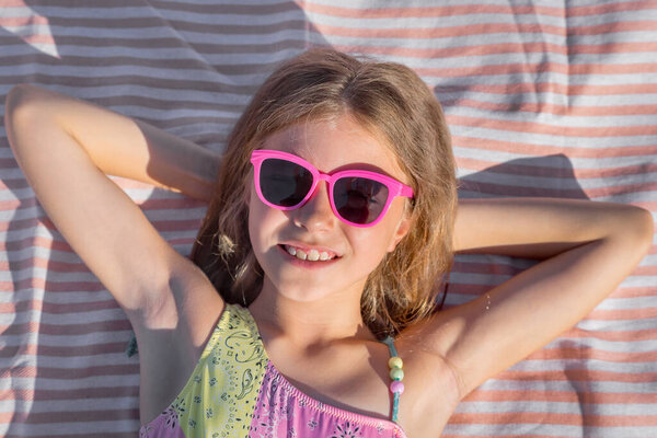 Portrait of a happy child on a beach towel with glasses. Top view.