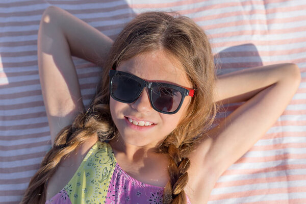 Portrait of a happy child on a beach towel with glasses. Top view.