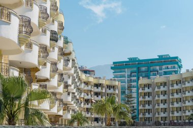 Palmiye ağaçları ve dağ manzaralı bir yerleşim yeri. Şehir manzarası.