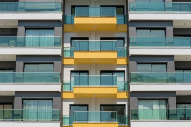 The front of a modern apartment building with glass balconies. Turkey real estate.
