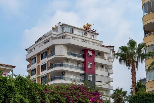 An inhabited low-rise building in southern Turkey. House surrounded by palms and flowers.