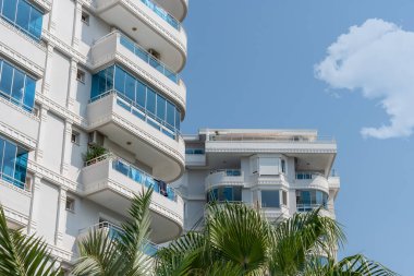 The facade of a white residential building with glazed balconies against the sky.