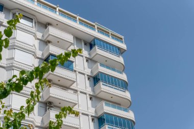 The facade of a white residential building with glazed balconies against the sky.