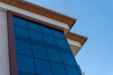 The glass facade of the building against the blue sky. Low angle view.
