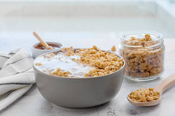 Сухие завтраки. Хрустящая чаша с мёдом и стакан молока на столе. Здоровая и волокнистая пища. Время завтрака