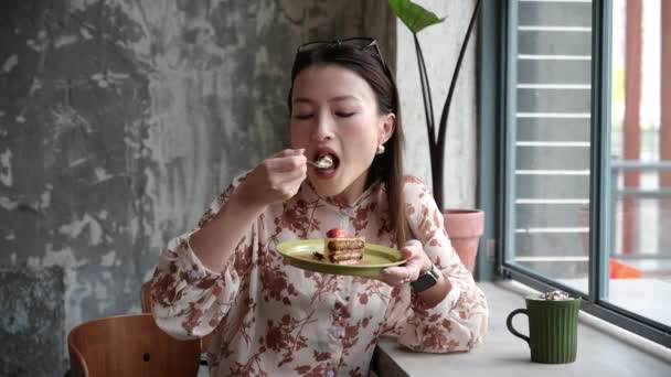 美丽的中国亚洲年轻女子去咖啡店吃甜点 令人叹为观止的女孩吃着蛋糕 喝着摩卡拿铁咖啡的肖像 商务女士在自助餐厅喝咖啡休息 — 图库视频影像