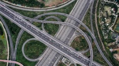 Metropolis 'teki çoklu şeritli otoyolun kavşağındaki insansız hava aracının yukarıdan görünüşü. Otobanlarda yoğun trafik var. Yüksek kıvrımlı yollar, yonca şekilli köprü hız sınırı yok..
