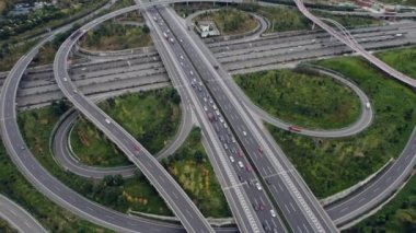 Metropolis 'teki çoklu şeritli otoyolun kavşağındaki insansız hava aracının yukarıdan görünüşü. Otobanlarda yoğun trafik var. Yüksek kıvrımlı yollar, yonca şekilli köprü hız sınırı yok..