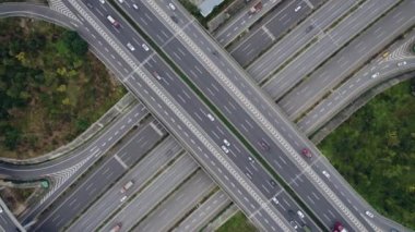 Metropolis 'teki çoklu şeritli otoyolun kavşağındaki insansız hava aracının yukarıdan görünüşü. Otobanlarda yoğun trafik var. Yüksek kıvrımlı yollar, yonca şekilli köprü hız sınırı yok..