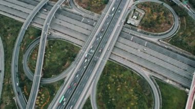 Metropolis 'teki çoklu şeritli otoyolun kavşağındaki insansız hava aracının yukarıdan görünüşü. Otobanlarda yoğun trafik var. Yüksek kıvrımlı yollar, yonca şekilli köprü hız sınırı yok..