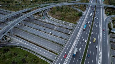 Metropolis 'teki çoklu şeritli otoyolun kavşağındaki insansız hava aracının yukarıdan görünüşü. Otobanlarda yoğun trafik var. Yüksek kıvrımlı yollar, yonca şekilli köprü hız sınırı yok..