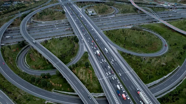 Metropolis 'teki çoklu şeritli otoyolun kavşağındaki insansız hava aracının yukarıdan görünüşü. Otobanlarda yoğun trafik var. Yüksek kıvrımlı yollar, yonca şekilli köprü hız sınırı yok..