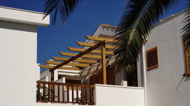 Pergola ve palmiye ağaçları olan ev balkonu.