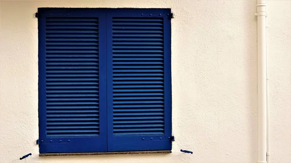 白いファサードの木製窓の青いシャッター — ストック写真