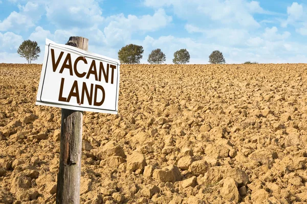 Plowed field with signboard and Vacant Land text - Land plot management - Real estate concept with a vacant land available for residential buildings construction