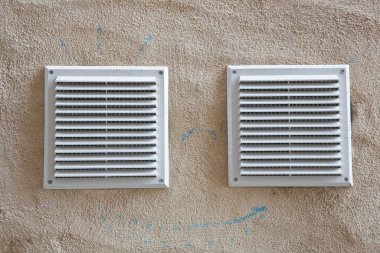 İç hava tahliyesi için beyaz plastik havalandırma ızgarası ve alçı bir duvara karşı böcek ağı ile kötü kokular.