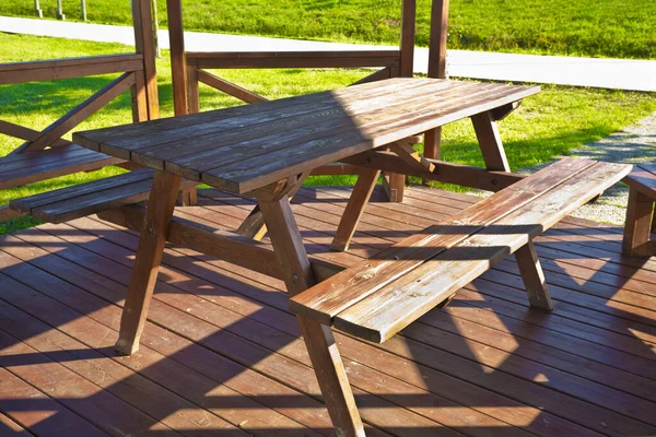 在公园的绿地上 一个木制露台上的木制野餐桌 — 图库照片