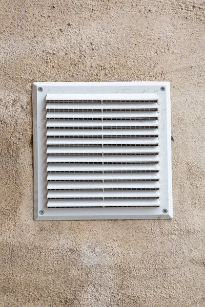 White plastic ventilation grille for internal air evacuation and bad smells with anti-insect net against a plaster wall