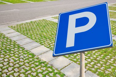 Parking areas with road sign and grey concrete permeable to rain flooring blocks assembled on a substrate of sand with grass