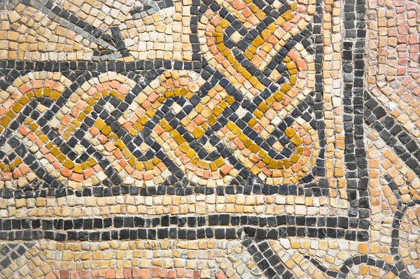 Ancient Italian Roman mosaic floor with circular shapes composed of small colored stone tiles - corner concept