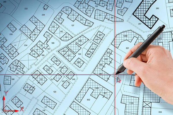 Imaginary cadastral map of territory with buildings and land plots drawn with a CAD (Computer-Aided-Design) computer software in dwg format file - concept with hand and digital pen