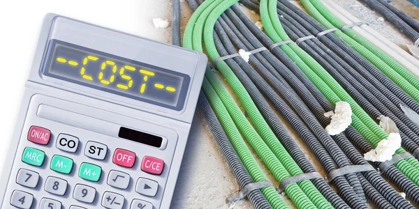 The cost of building a new electrical system - concept with corrugated and flexible plastic pipe for electrical wiring and cables in a construction site with calculator