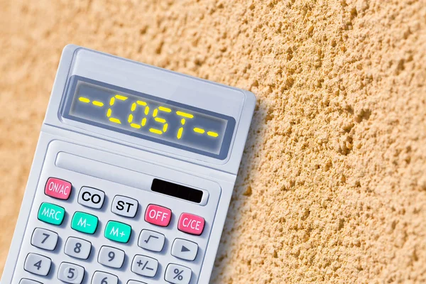 Costs for construction of a new plaster wall with grainy effect surface - macro photography with shallow depth of field and calculator
