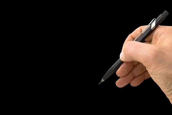 Male hand writing with a black pencil on black background - concept with copy space