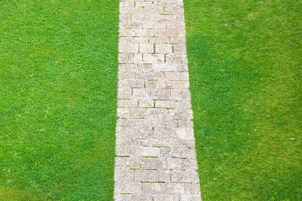 Pedestrian old stone footpath on a grass area of a public park