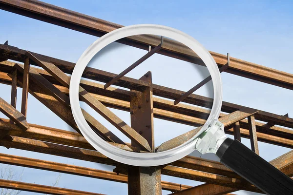 Attention and surveillance of old steel structures - concept with old beams and metal profiles seen through a magnifying glas