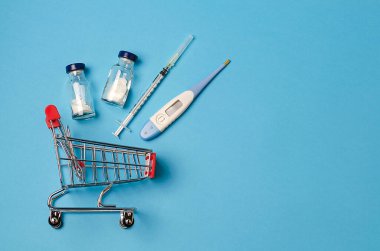 Mavi tıbbi geçmişinde, aşıyla, şırıngayla, termometreyle dolu bir süpermarketten alınmış tıbbi bir araba var. Konsept: Aşı ve uyuşturucu teslimatı. Zorunlu aşı