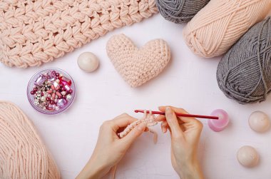 Kendi ellerinle örgü ördün. Pembe ve gri iplikler ördün. Örgü örülmüş eşarp. Kadın elleri örgü kancası ve örgü örer. Karantina sırasında kış aktiviteleri. Aşk günü. Aşk kalbi..