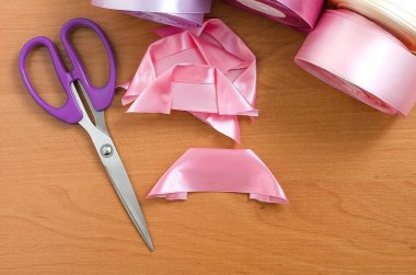 Adım adım talimat. Rosette saten kurdeleden yapılmış. El yapımı el sanatları. Şeftali arkaplan. Pembe renkler, pembe kurdeleler. Yaratılış. Kurdeleden, kumaştan on sentlik çiçekler. Altıncı adım