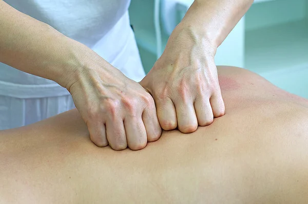 Woman professional masseur shows massage techniques. Back massage for the purpose of healing, muscle relaxation and treatment.