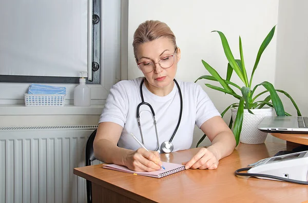 Woman doctor writes out a prescription with medicines to a patient. The family doctor keeps records of the sick patient.