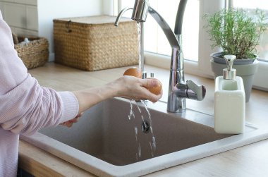 Kız akan suyun altında yumurta yıkıyor. Salmonella 'ya karşı savaş. Mutfakta temizlik ve temizlik var..