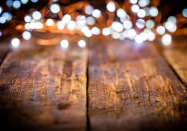 Beyaz ve altın çözünmüş ışıklardan oluşan Noel çelengi eski, eskimiş eski siyah masa veya ahşap kahverengi tahta üzerinde. Noel süsü, yeni yıl arifesi. Seçici odak, bokeh, metin için boşluk.