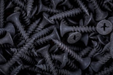 Bir hırdavat dükkanının tezgahındaki siyah kendini beceren vidaları kapat. Vidaların arkaplanı.