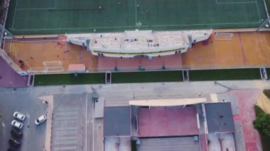 Yerel bir takımın oynandığı bir futbol sahasının üzerinde havadan çekim yapılıyor, kamera sahada konumlanana kadar ilerliyor ve bir takım saldırırken gözlemleniyor.