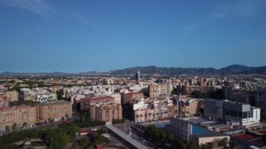 Murcia şehrinin havadan görüntüsü, görüntünün merkezinde iki gökdelen görüyoruz ve kamera yükseliyor, parkları ve caddeleri keşfediyor, arka planda Murcia 'nın bahçesini görüyoruz, Vega Baja del Segura' yı ve dağları. 