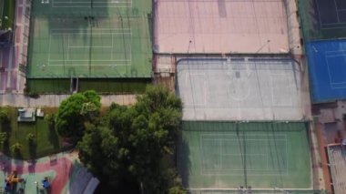 Hava aracı görüntüsü tenis kortlarının, kapalı alanda futbolun, basketbolun ve hokeyin geçtiği bazı spor tesislerinden geçiyor. Sahnenin sonunda futbol oynayan bazı insanlar görüyoruz.